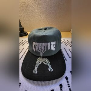 Creature Rolling in the grave, green and black snapback hat (Zumiez)